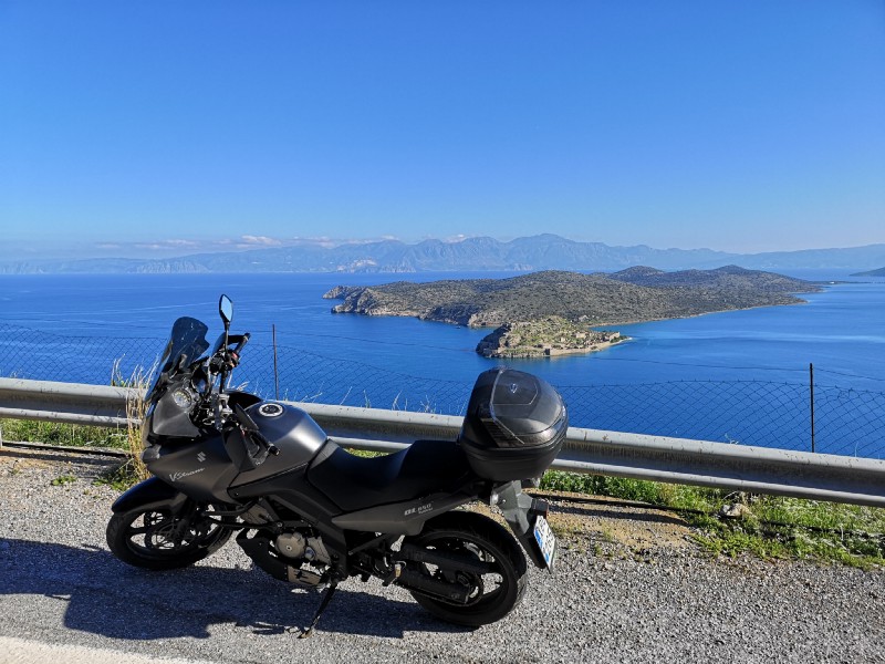 A motorbike parked on the road with a sea in the background